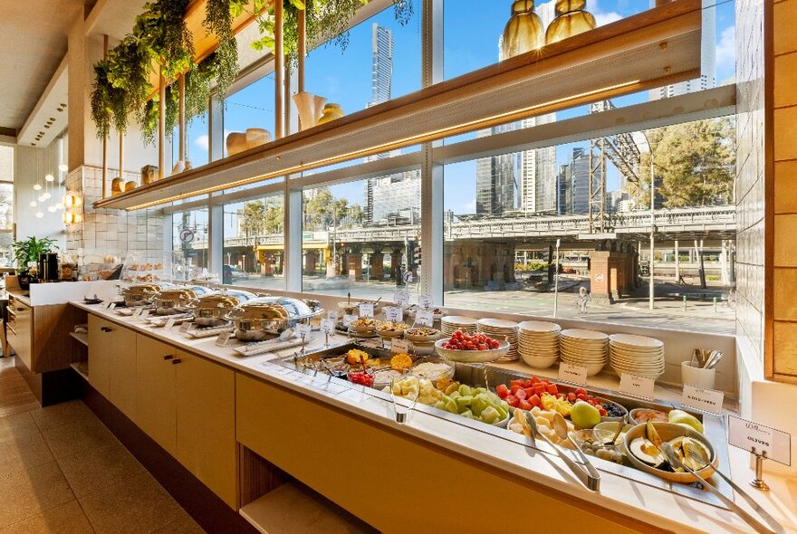 Long buffet bar with heated dishes and salad bar, large windows looking onto the city streets.