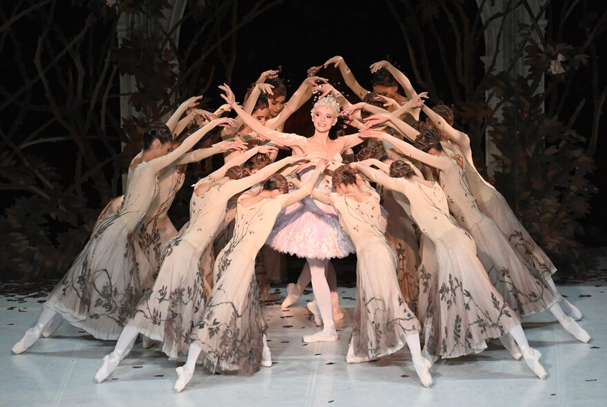A ballet company performing on stage with ballerinas forming a guard around a central dancer. 