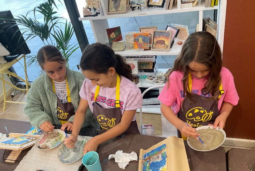 Three kids all partaking in a chocolate decorating activity. 