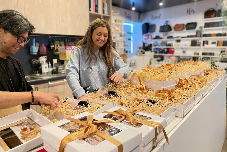 People laughing as they wrap lots of gift boxes,