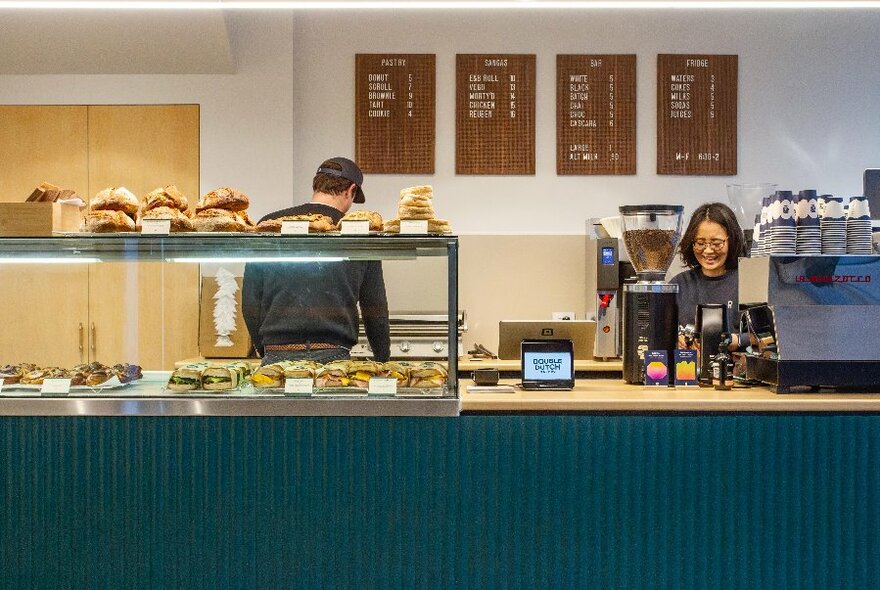 Bakery interior with staff working behind a bain-marie and coffee bar.