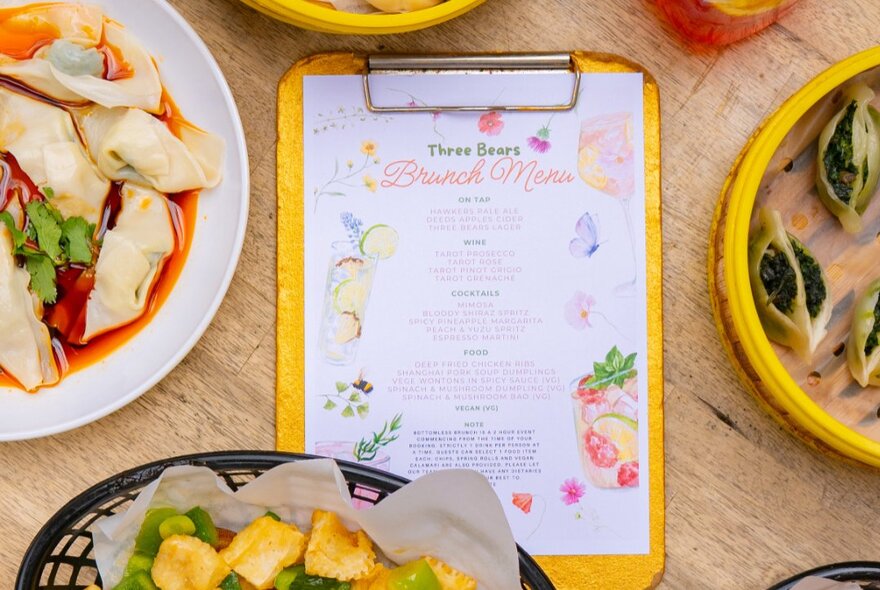 Dishes of food and menu with illustrations on a wooden table.