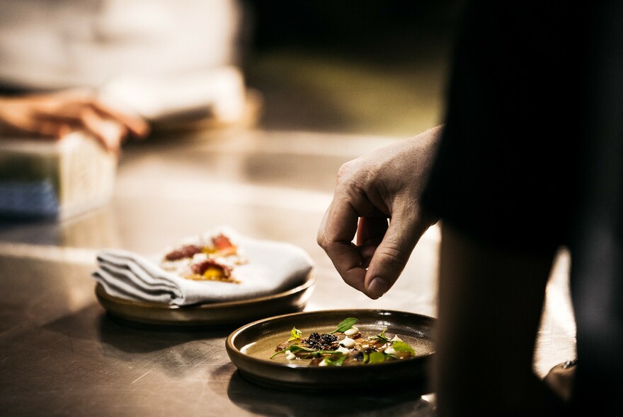 Hand above a plate of leaves and spices.