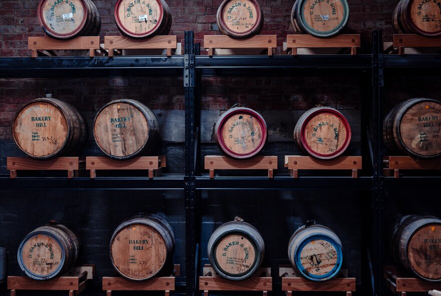 Whisky barrels stacked on large shelves in an underground cellar.