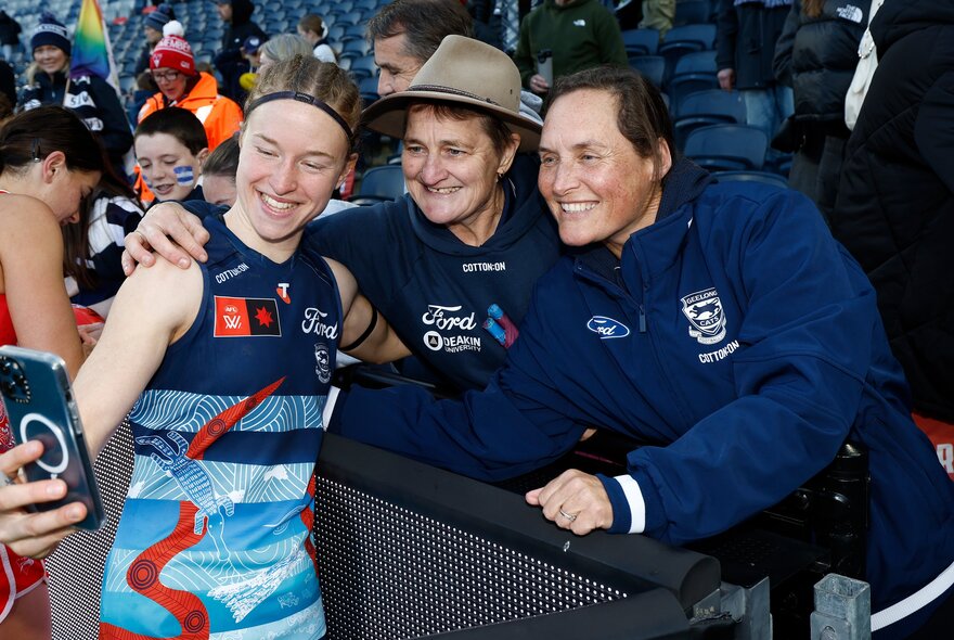 Geelong AFLW football player taking a selfie with fans in the stands.