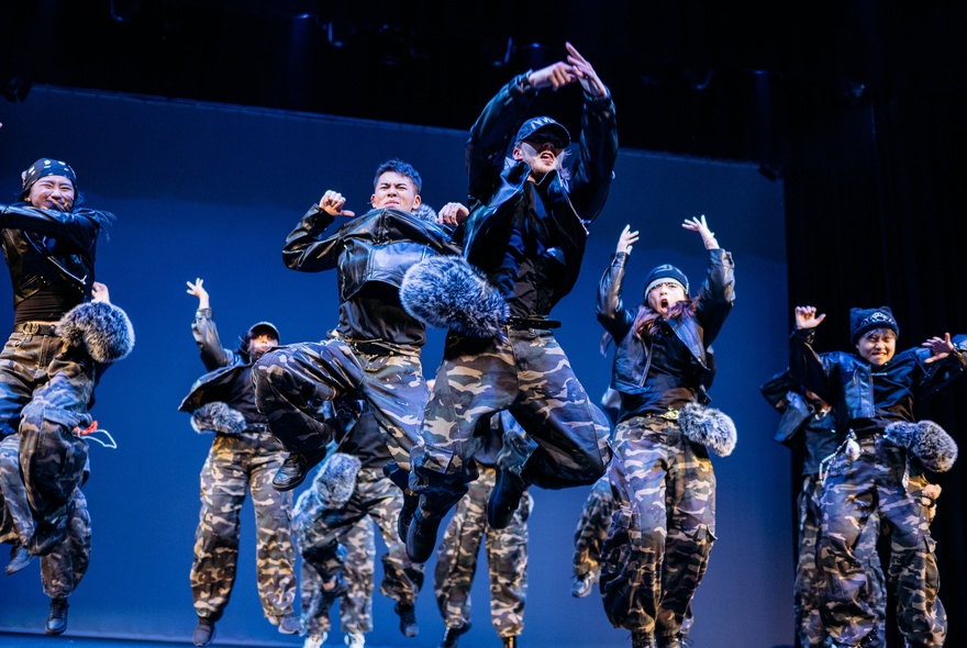 Dancers performing on stage, leaping into the air at once.
