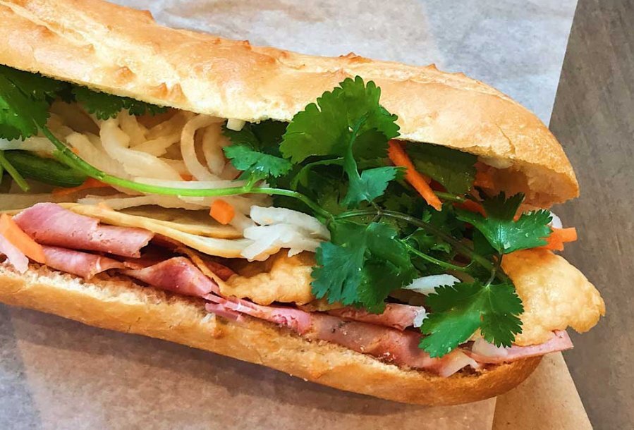 A bread roll filled with salad and deli meats