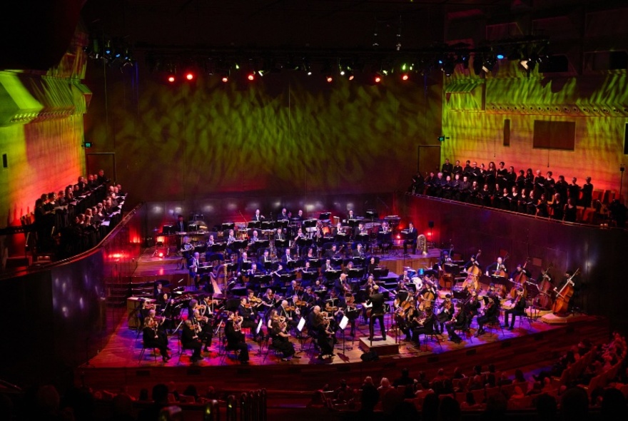 A symphony orchestra playing their instruments on a stage.