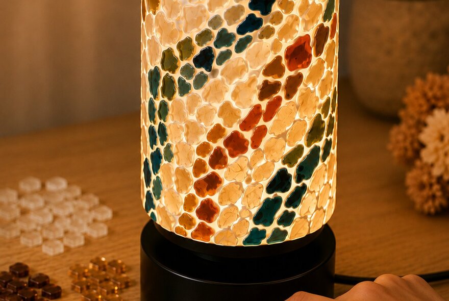 A cylindrical mosaic glass table lamp featuring a colourful striped pattern, being made at a craft workshop.