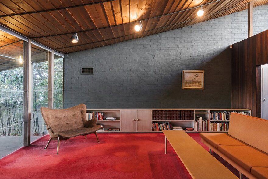 The retro interior of a 1950s home with red carpet and amber chairs. 