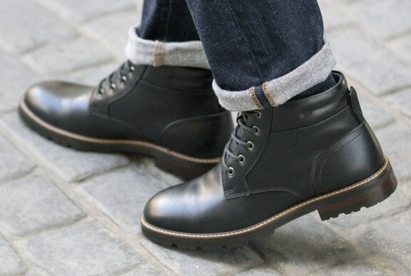 Men's short lace-up black boots worn with turn-up jeans.