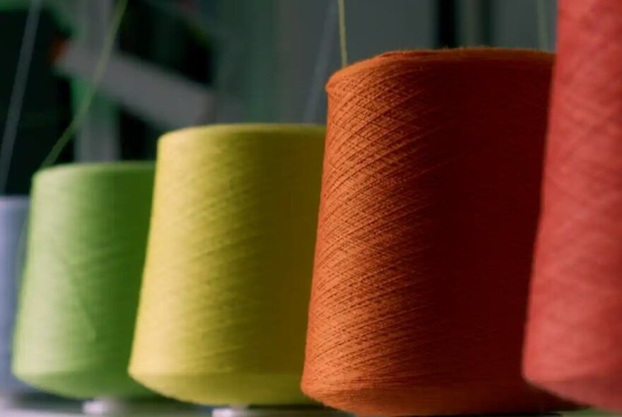 Four large cones of coloured yarn inside a knitting studio.