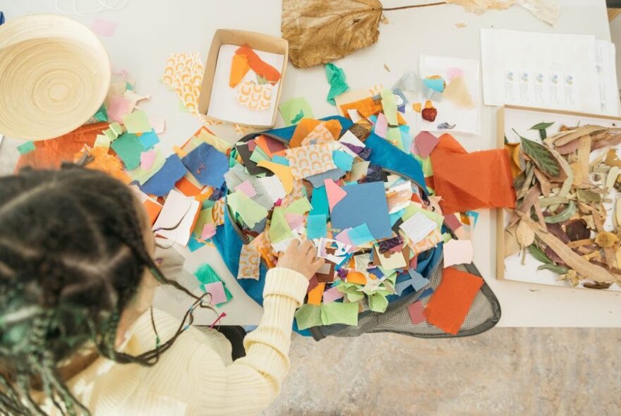 A young girl playing with paper and craft materials.