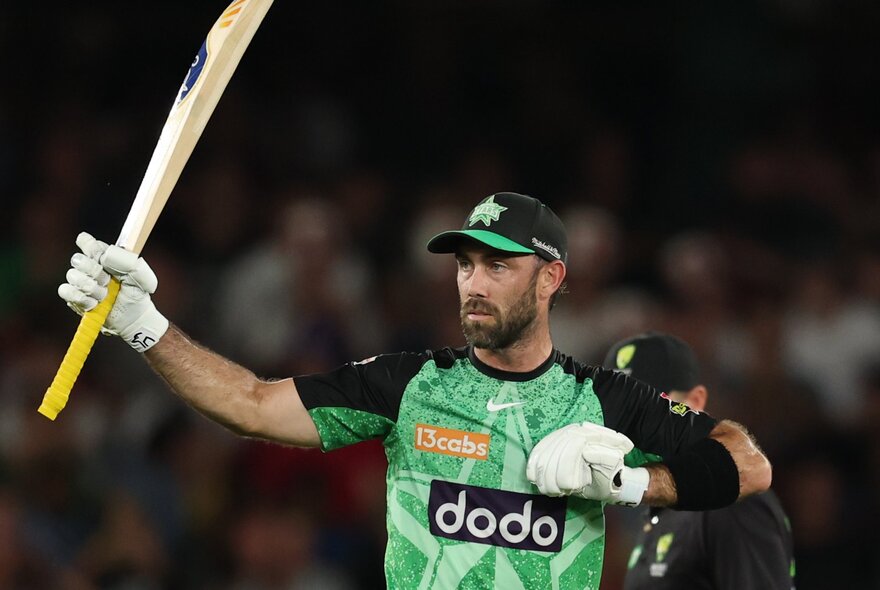 A Melbourne Stars cricketer holding up a bat at a game. 