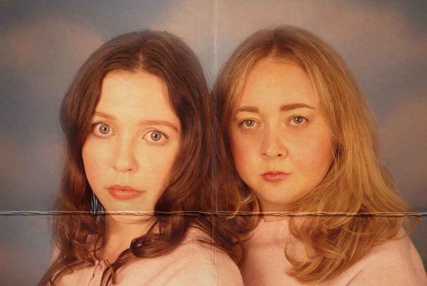 Faded picture of two women staring blankly with a fold mark down the middle. 
