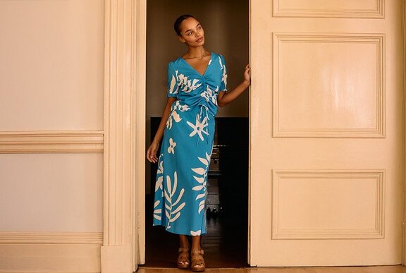 A model posing in a matching blue skirt and top with white leaf print.