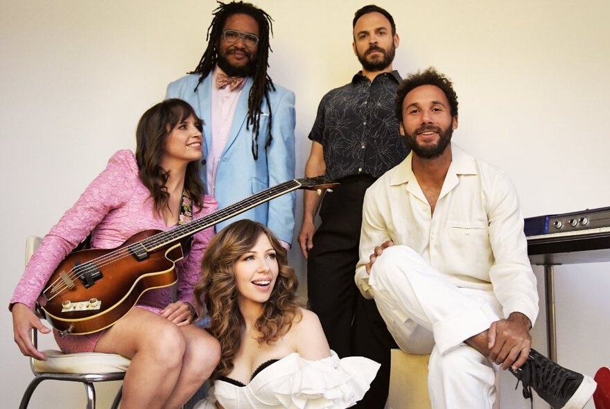 The five members of the band Lake Street Dive posing for a group photo, one of them holding an electric guitar.