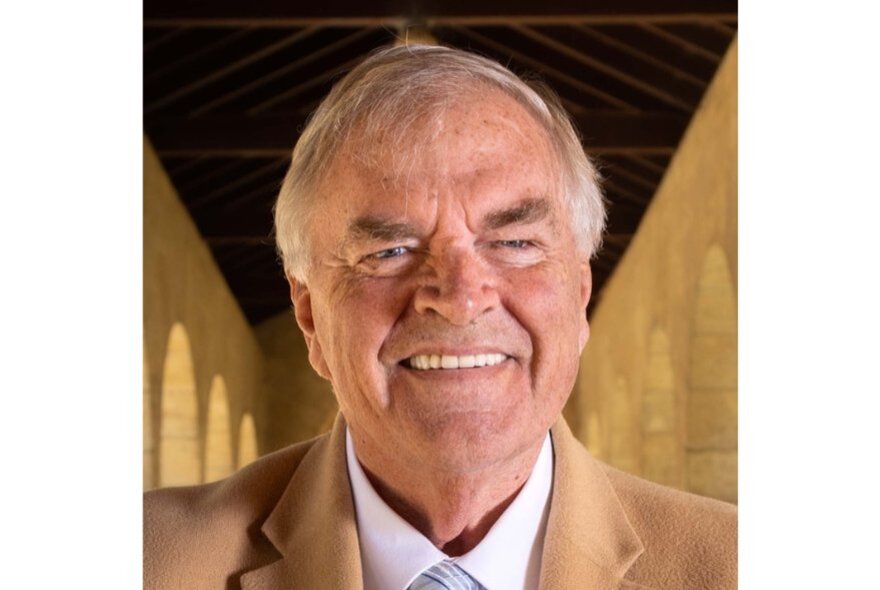 Smiling Kim Beazley wearing camel-coloured jacket and shirt with tie.