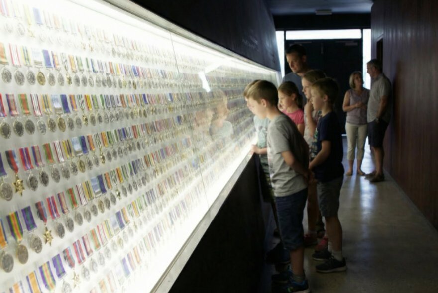 Children looking at walls of illuminated medals.