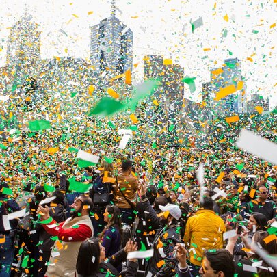 A large crows celebrates Indian Independence Day in Federation Square as a load of orange, green and white confetti falls from the sky. 