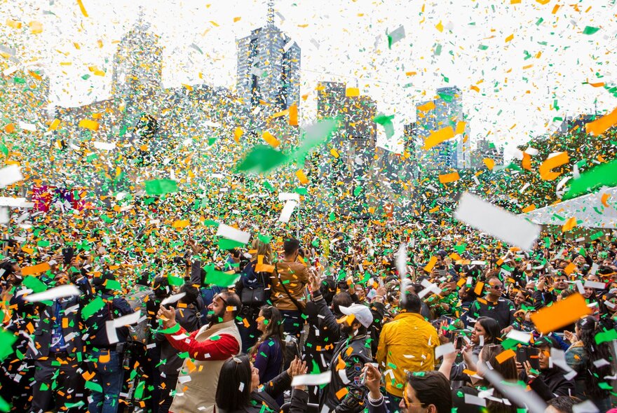 A large crows celebrates Indian Independence Day in Federation Square as a load of orange, green and white confetti falls from the sky. 