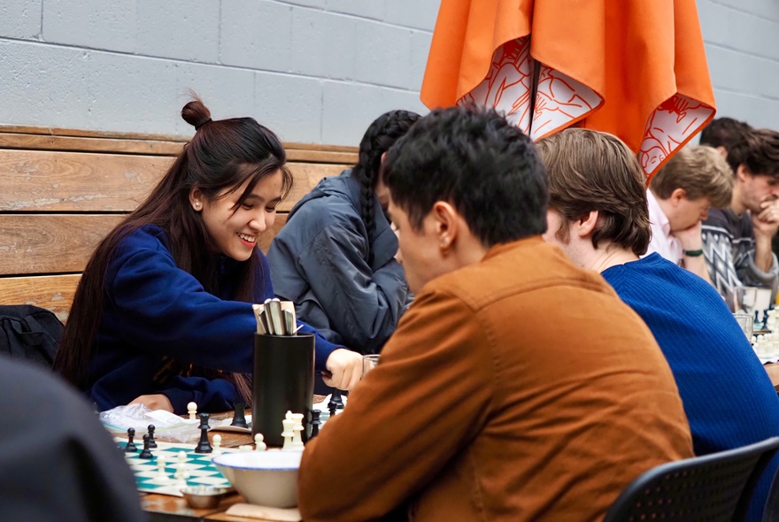 Groups of chess players seated at outdoor tables.