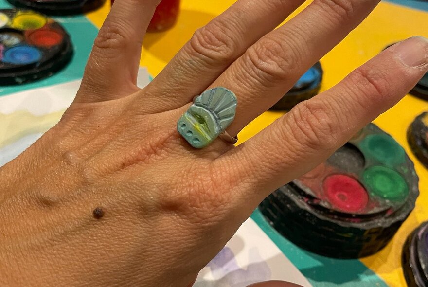 A hand modelling a ring that has been carved from soapstone.