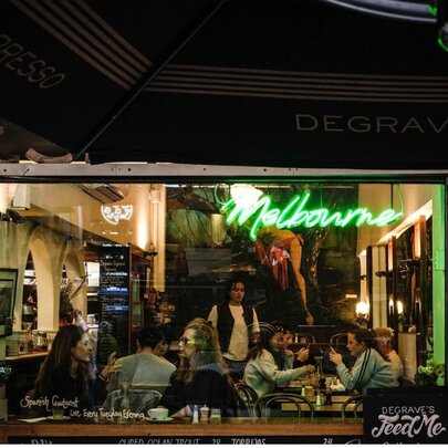 A cafe in Melbourne's Degraves Street at night, with patrons seen dining in the cafe through the large window.