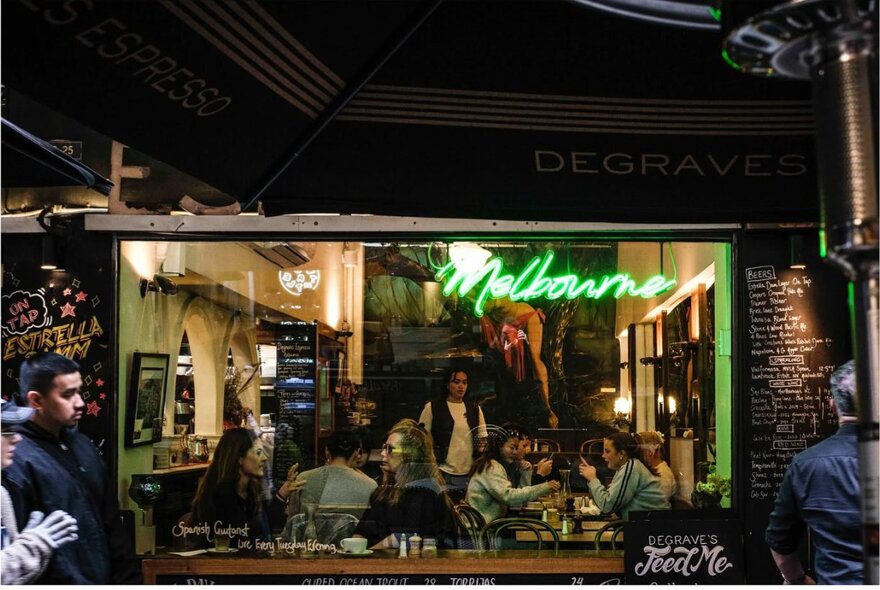 A cafe in Melbourne's Degraves Street at night, with patrons seen dining in the cafe through the large window.