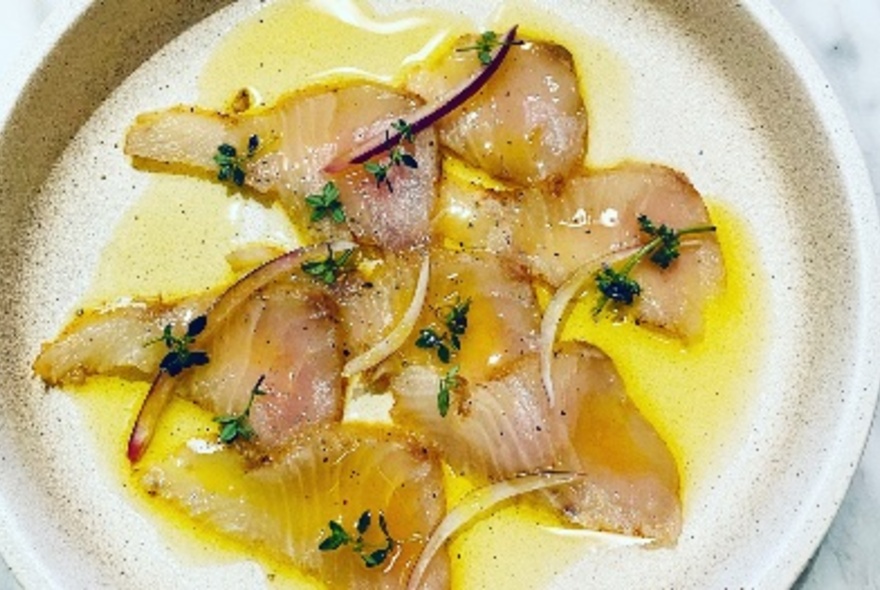 Plate of slices of fish in a yellow sauce.