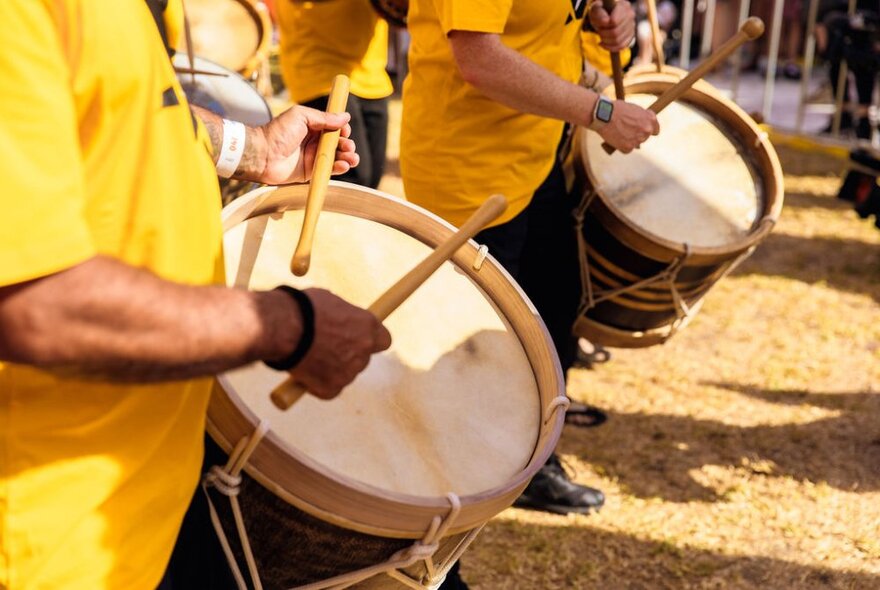 Close-up of drummers wearing yellow shirts with Brazilian drums.