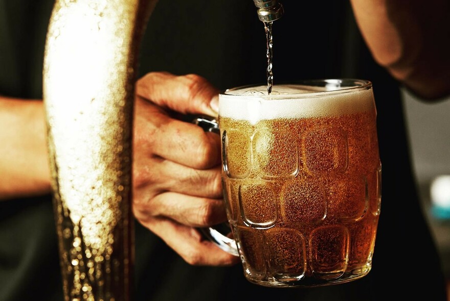 Beer being pored into a a dimple glass pint mug.