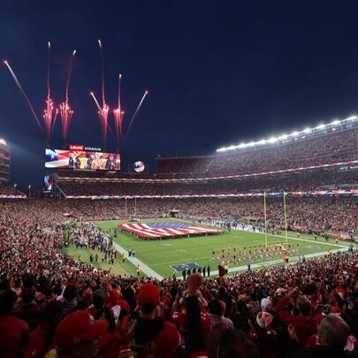 Huge sports stadium filled with fans as fireworks explode over a huge screen.
