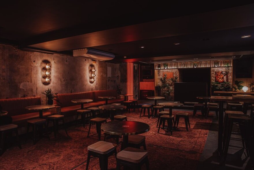 Dimly lit underground bar, with bench, stool and table seating.