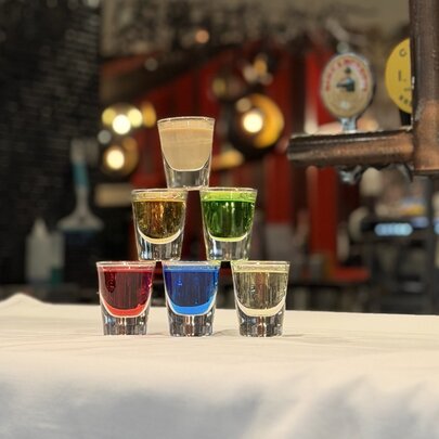 A stacked tower of colorful alcoholic shots on a bar.