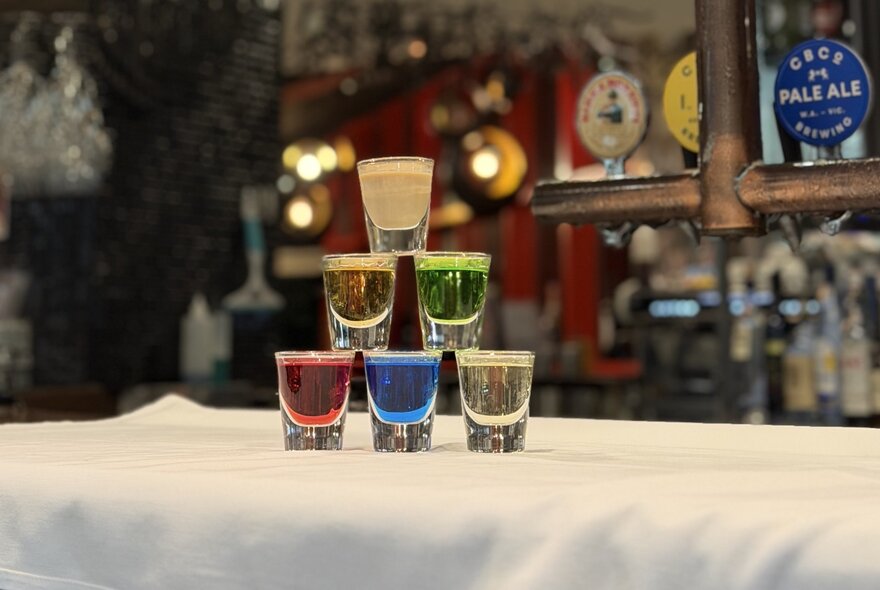 A stacked tower of colorful alcoholic shots on a bar.