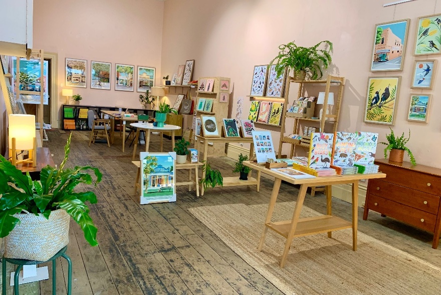 The interior of a gift shop with items for sale on shelves, tables and small framed artwork on the walls.