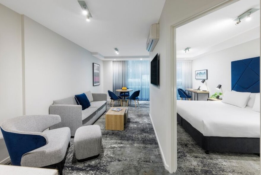 Hotel apartment-style accommodation with a wall separating the bedroom from a lounge area with sofa and seating.