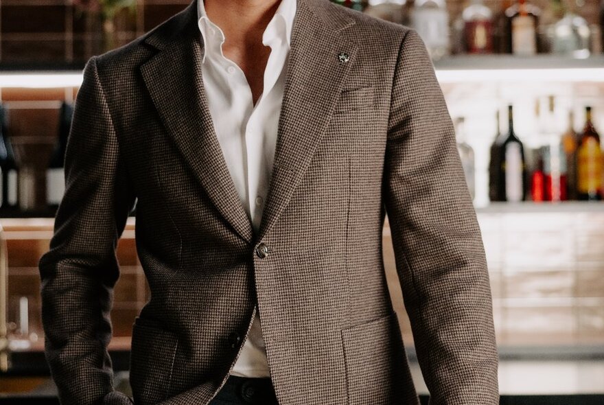 A person modelling a light brown coloured suit jacket, with one button done up.