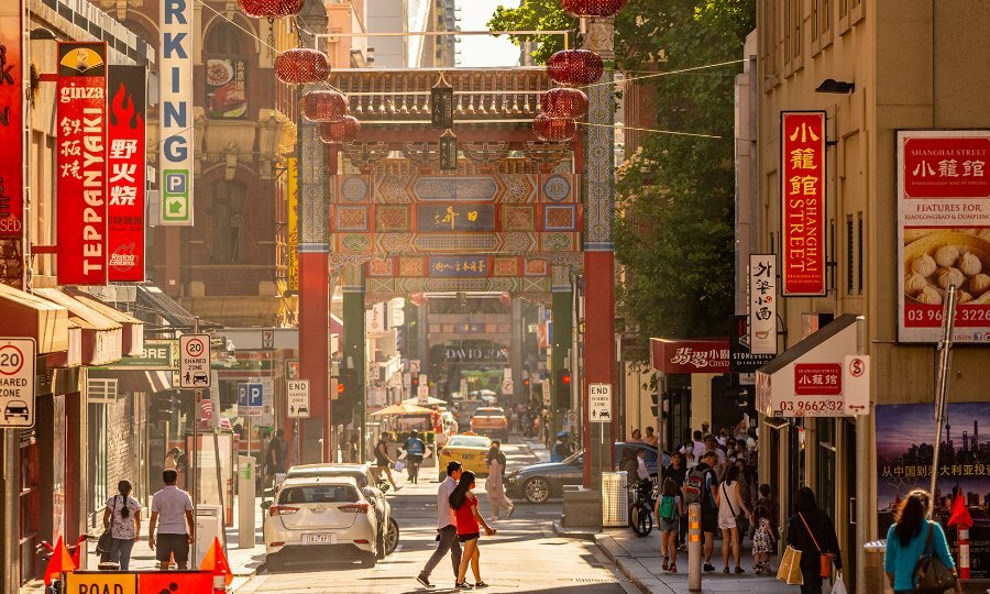 A busy Chinatown street with lanterns and restaurant signs. 