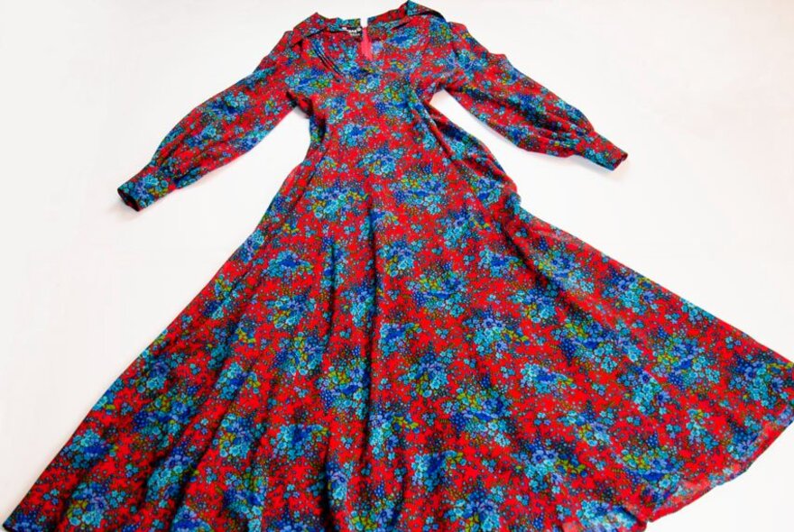 A full-length, vintage-style maxi dress with a vibrant red background and a blue and green floral pattern.