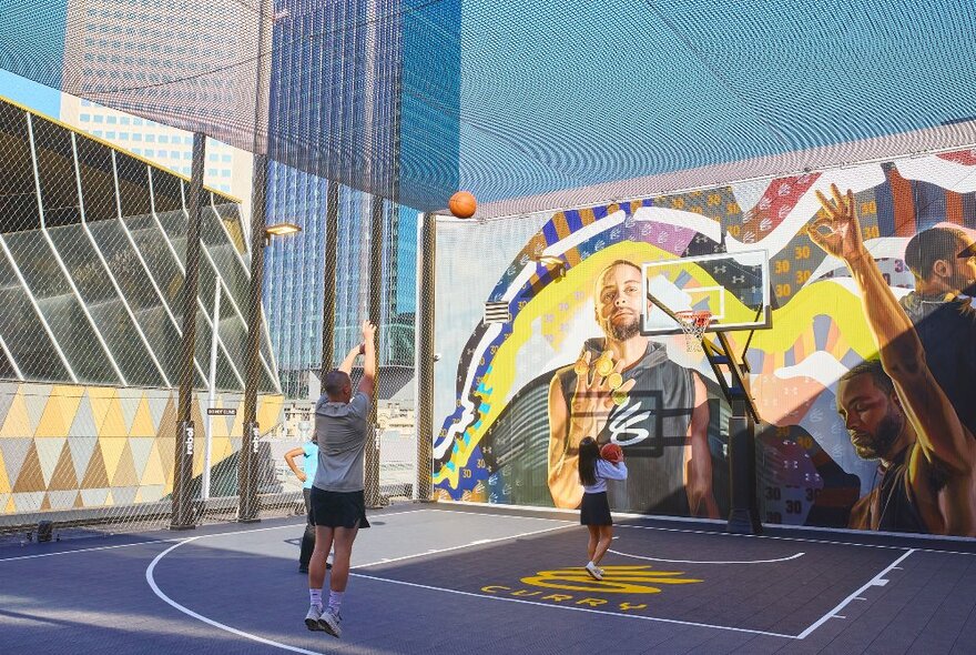 A group of friends are playing basketball on a rooftop basketball court