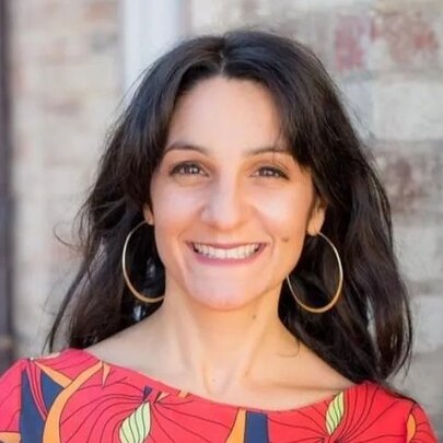 Presenter Paola Di Trocchio, with long dark hair, large hoop earrings and cerise patterned top.