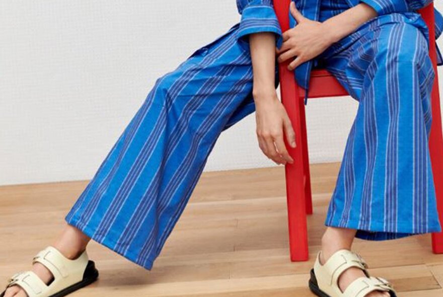 A woman is sitting on a chair in blue striped pants