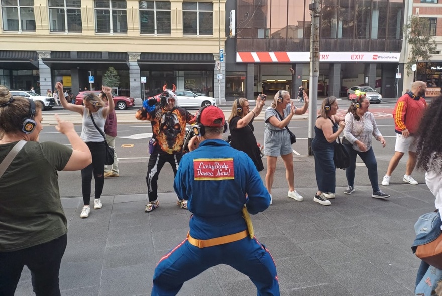 Group of disco walking tour participants dancing in the street beside a main road in Melbourne.