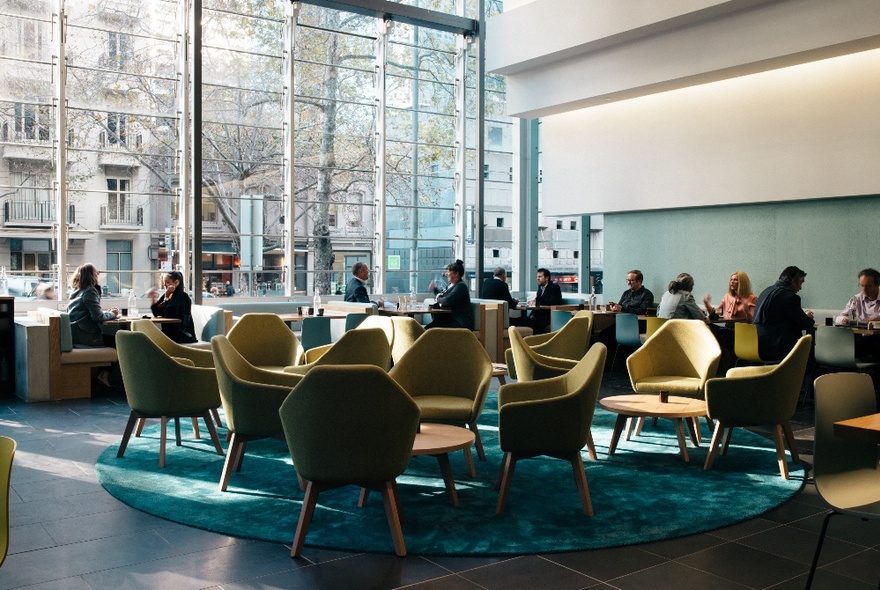 Interior of Axil Coffee Lonsdale St, with people seated in club chairs next to large windows, enjoying coffee.