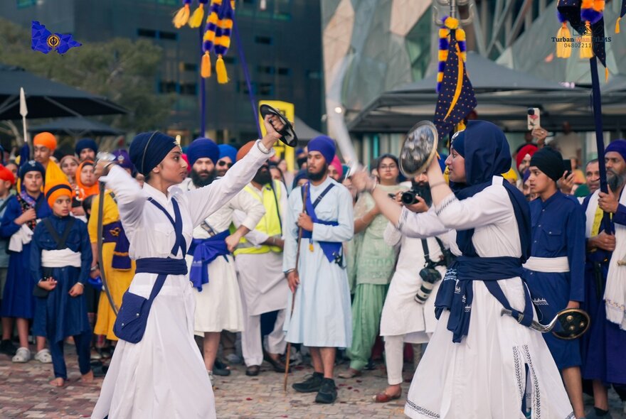 A Sikh festival in Federation Square with people dancing in traditional costumes.