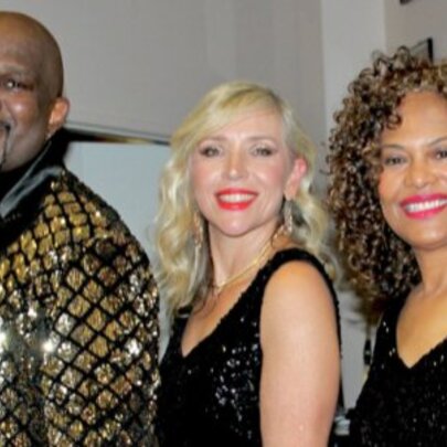 Two female and one male soul singer, male wearing glittering tux and yellow tie, women wearing black gowns.