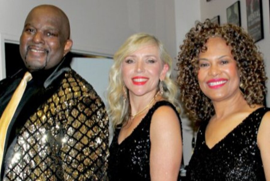 Two female and one male soul singer, male wearing glittering tux and yellow tie, women wearing black gowns.