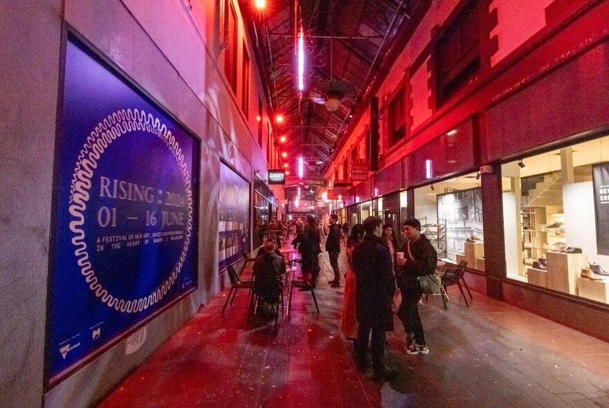A laneway lit up red with people milling around.